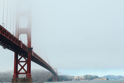 Low angle view of golden gate bridge against sky during foggy weather