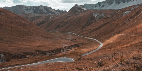 Scenic view of road by mountains against sky