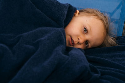 Child wrapped in dark towel after swimming in pool, filling cold. toddler girl portrait laying on