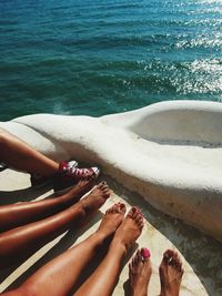 Low section of woman relaxing by sea