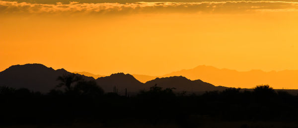 Scenic view of silhouette mountains against orange sky