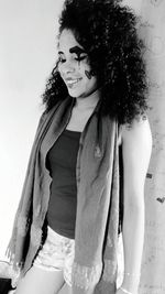 Portrait of young woman standing against white wall