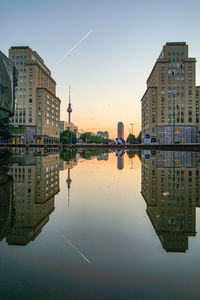 Reflection of buildings in pond against clear sky