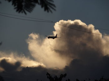 Low angle view of silhouette airplane flying against sky during sunset