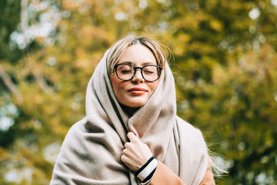 Portrait of young woman wearing sunglasses standing against plants