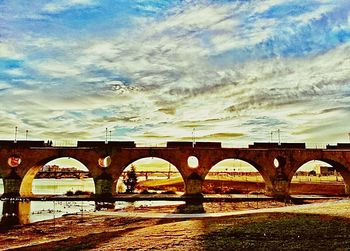 Bridge over river against cloudy sky