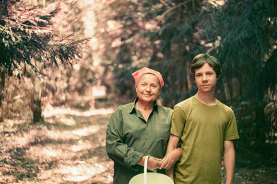 Portrait of mother and son standing against trees in a forest