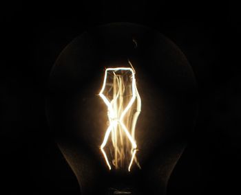 Close-up of lit light bulb in the dark