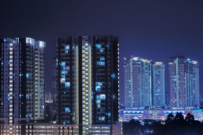 Illuminated buildings in city against sky at night