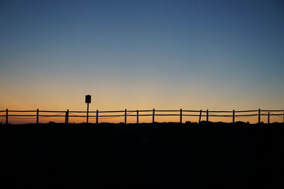 Low angle view of electricity pylon against clear sky during sunset