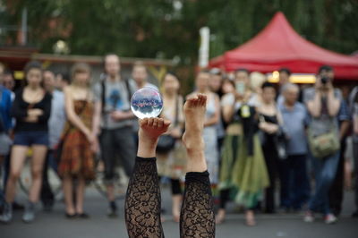 Low section of street performer woman balancing crystal ball on foot