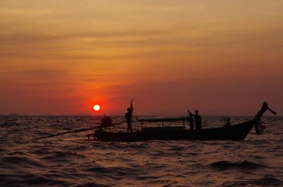 Silhouette men over boat on sea against sky