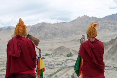 Rear view of man standing on landscape against mountains