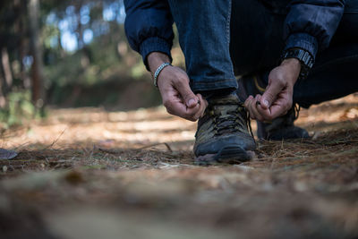 Low section of man tying shoe on field