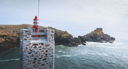 Lighthouse by sea against sky