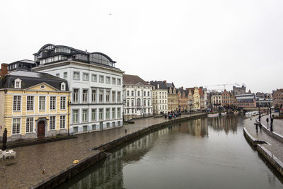 Canal amidst buildings against clear sky