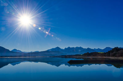 Scenic view of lake and mountains against blue sky