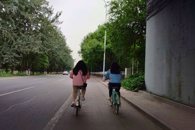 Rear view of woman riding bicycle on road