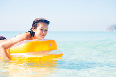 Portrait of smiling young woman in sea against clear sky