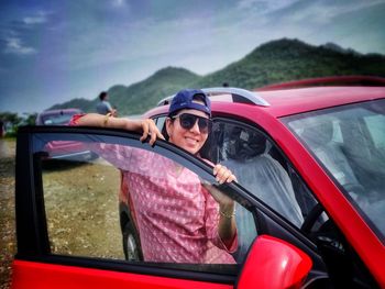 Portrait of smiling woman sitting on car