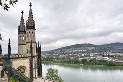 Buildings at waterfront against cloudy sky