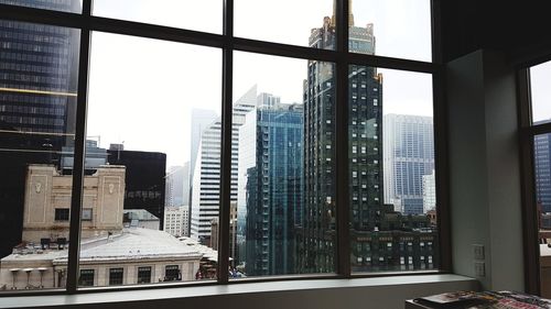 Buildings against sky seen through glass window