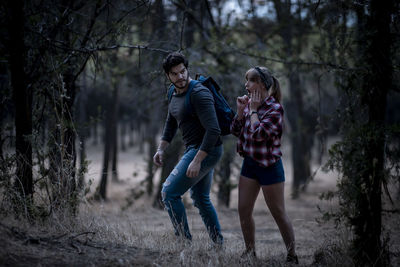 Man and woman running on street amidst trees in forest