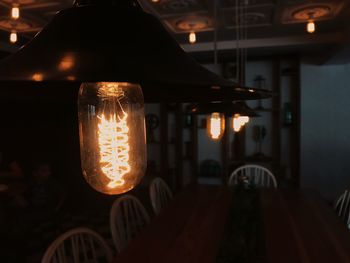 Close-up of illuminated light bulb hanging at night
