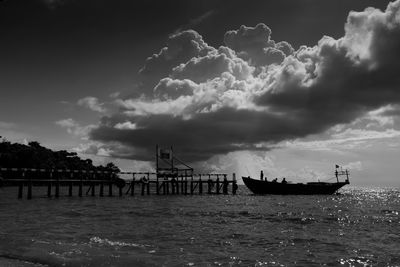 Pier on sea against cloudy sky