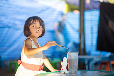 Girl looking away while standing at table