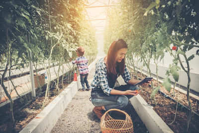 Woman sitting by plants against trees