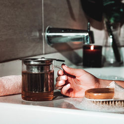 Cropped hand of woman having drink in bathtub