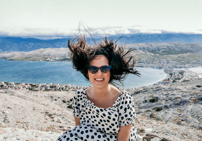 Portrait of smiling young woman on beach against sky