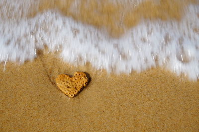 Close-up of heart shape on sand at beach