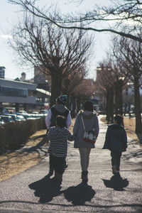 Rear view of father and son walking on sidewalk