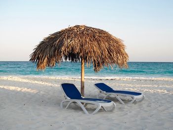 Lounge chairs on beach against sky