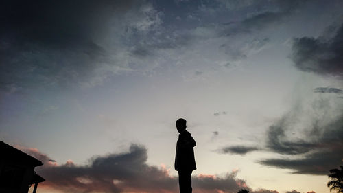 Low angle view of silhouette man standing against sky during sunset