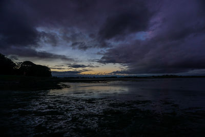 Scenic view of lake against cloudy sky at dusk