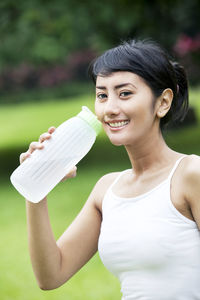 Portrait of smiling young woman drinking water from bottle