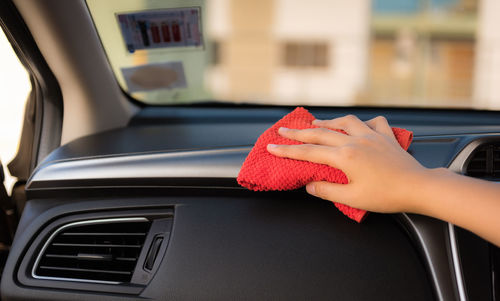 Cropped hand of person cleaning dashboard in car