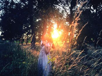 Woman on field against sky during sunset