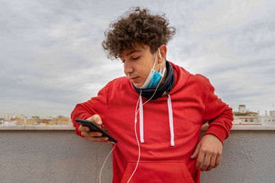 Young woman using mobile phone against sky