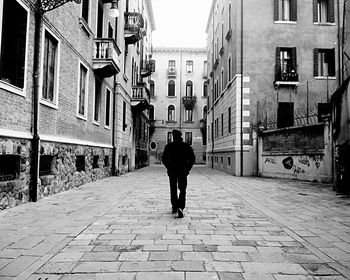 Rear view of man walking on street in city