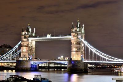 Illuminated tower bridge over thames river against sky at night