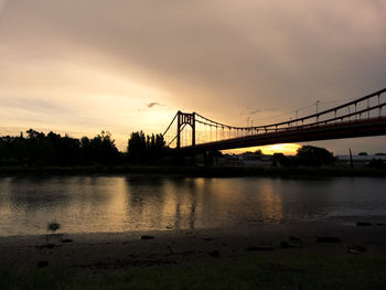 View of bridge over river at sunset