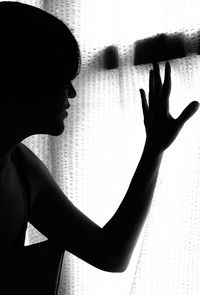 Silhouette woman touching window curtain