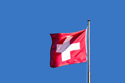 Low angle view of flag against clear blue sky