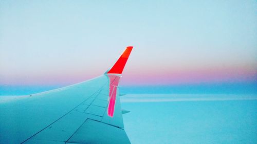 Close-up of airplane flying over sea against clear sky