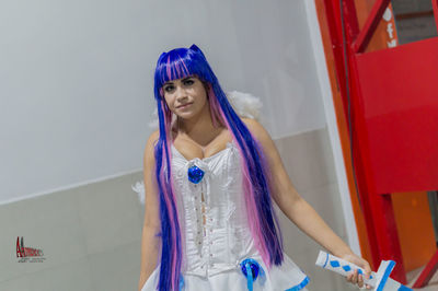 Portrait of young woman standing against blue wall