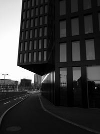 Road by buildings against clear sky